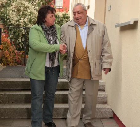 Eine Pflegerin hilft einem Gast die Treppe hinunter. Sie unterhalten sich freundlichen dabei.