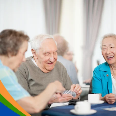 Ältere Menschen spielen Karten und genießen Zeit miteinander in einem hellen Raum.